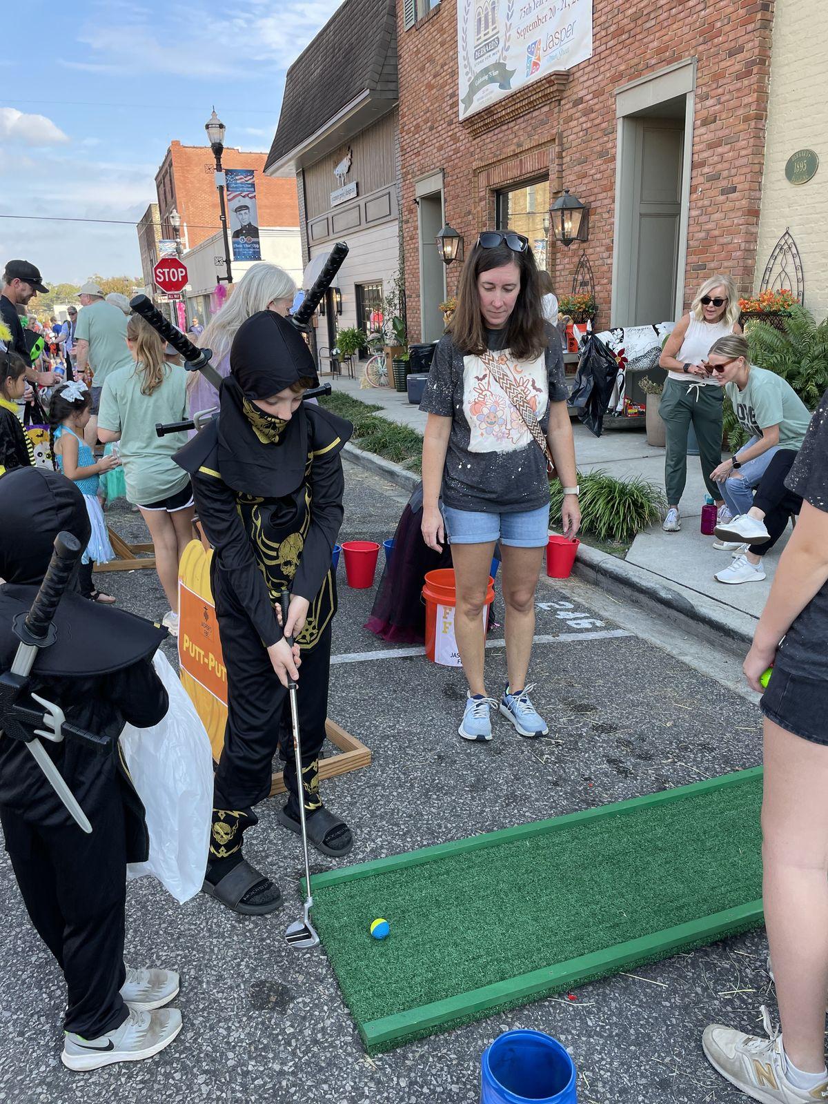 Kid playing putt-putt on downtown street